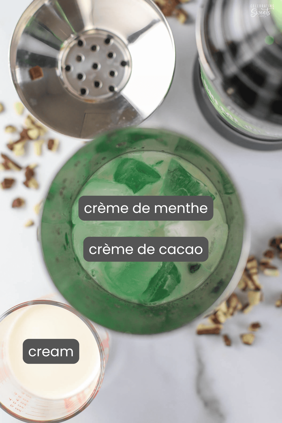 Ingredients for a grasshopper cocktail: a cocktail shaker filled with ice and green liqueur next to a small glass of cream.