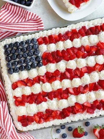 American flag cake decorated with strawberries, blueberries and white frosting.