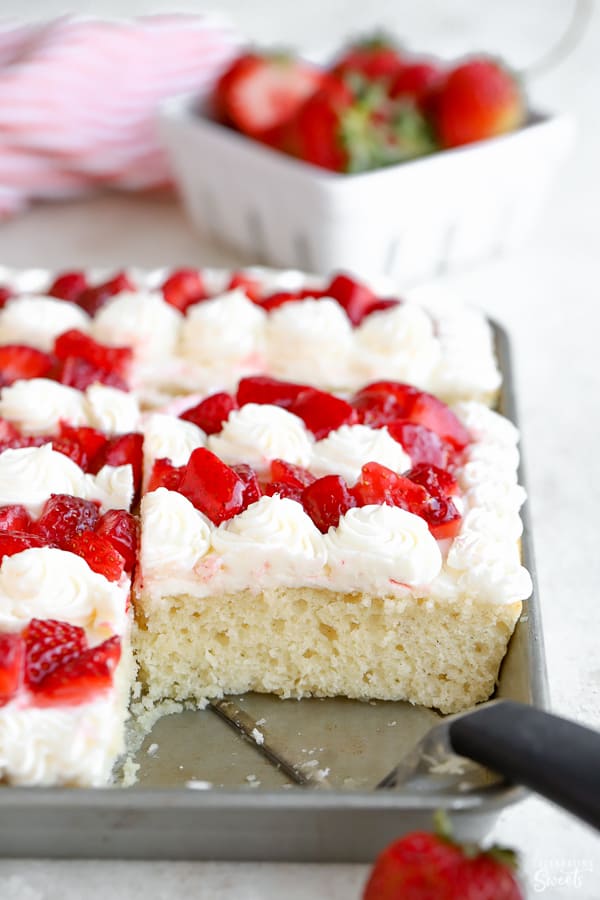 Vanilla sheet cake topped with vanilla frosting and chopped strawberries.
