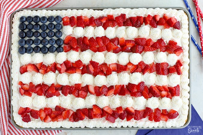 American flag cake decorated with strawberries, blueberries and white frosting.