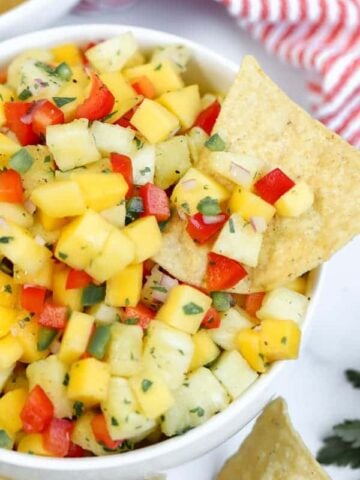 Bowl of pineapple mango salsa with a tortilla chip.