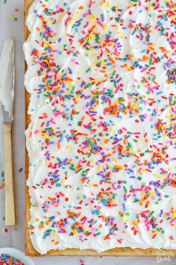 Vanilla sheet cake topped with vanilla frosting and sprinkles. 