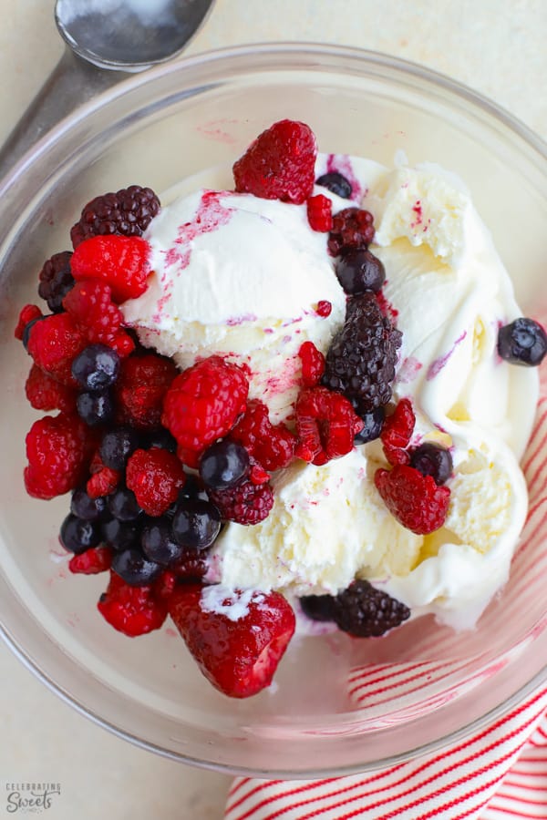 Large bowl of vanilla ice cream topped with frozen berries.