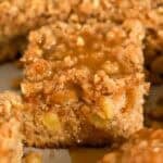 Apple crumb cake topped with brown sugar sauce in a metal baking pan.