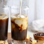 Milk being poured into iced coffee