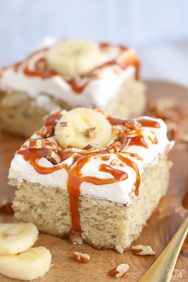 Slice of banana cake topped with caramel, nuts and sliced banana.
