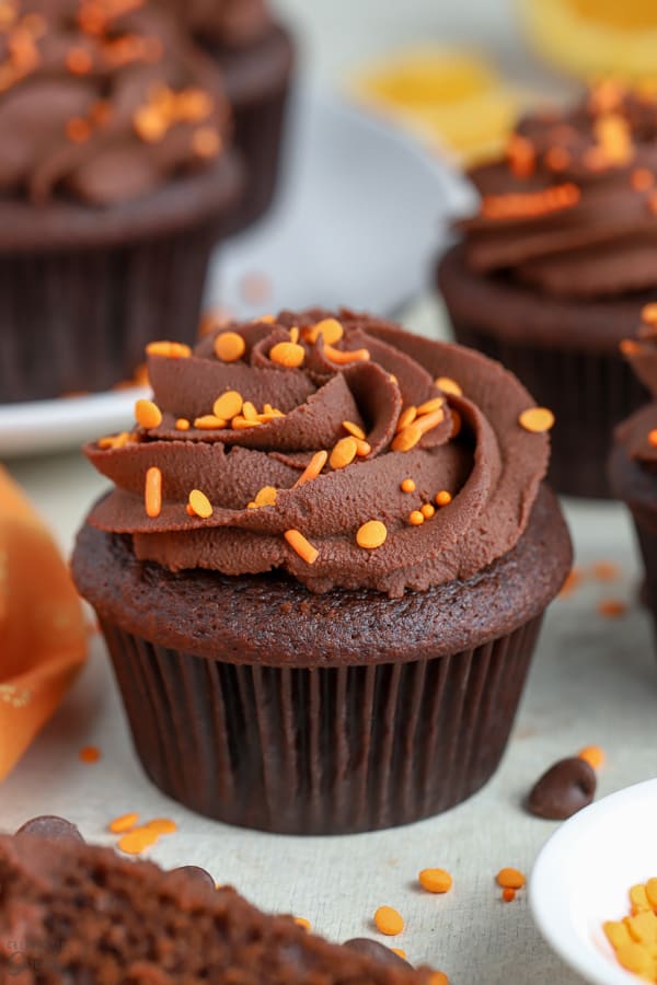 Chocolate orange cupcake topped with chocolate frosting and orange sprinkles.