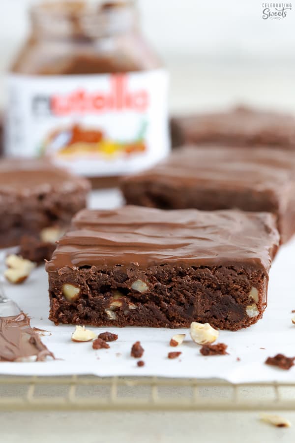 Brownie topped with chocolate frosting on a piece of parchment paper.