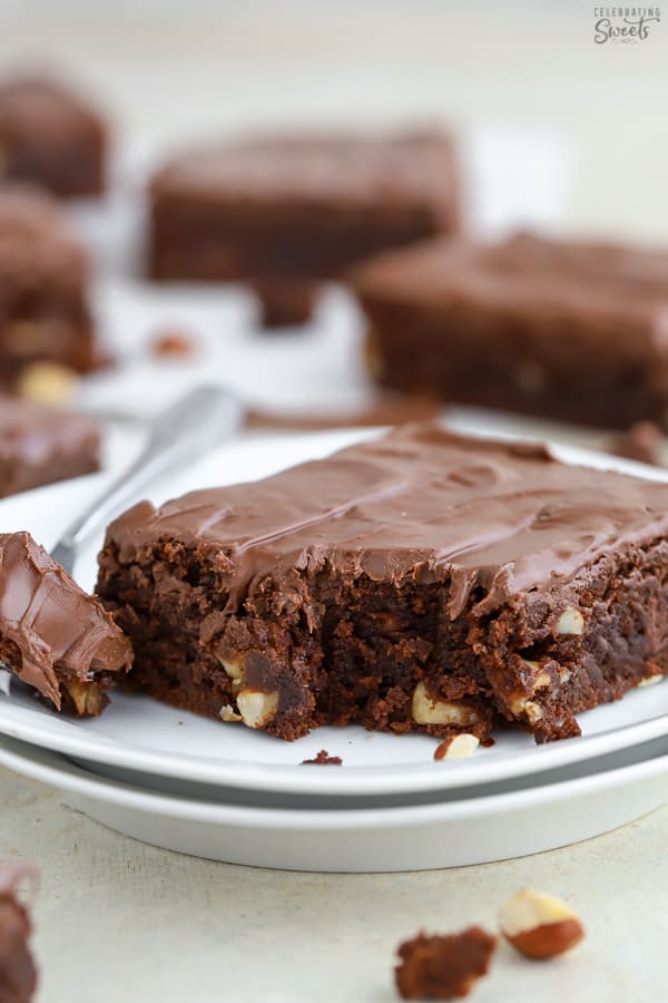 Slice of a brownie on a white plate with a fork.
