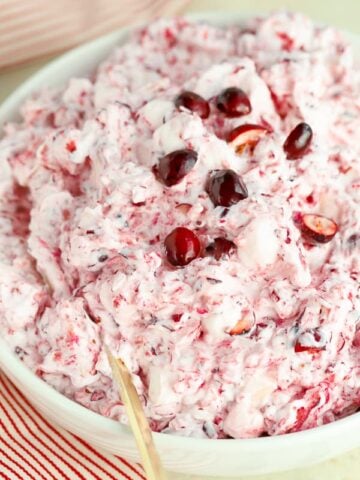Creamy cranberry salad in a white bowl with a gold spoon.