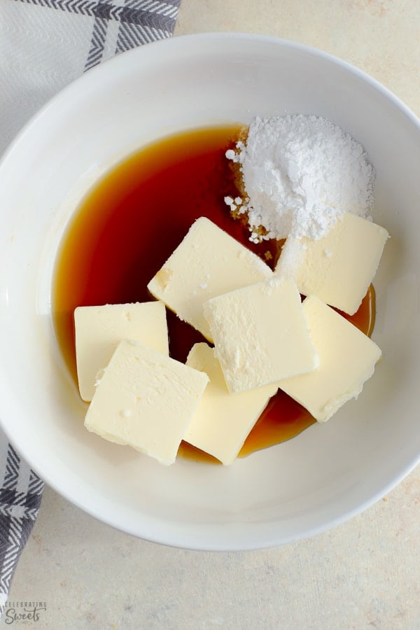 Butter, maple syrup and powdered sugar in a white bowl.