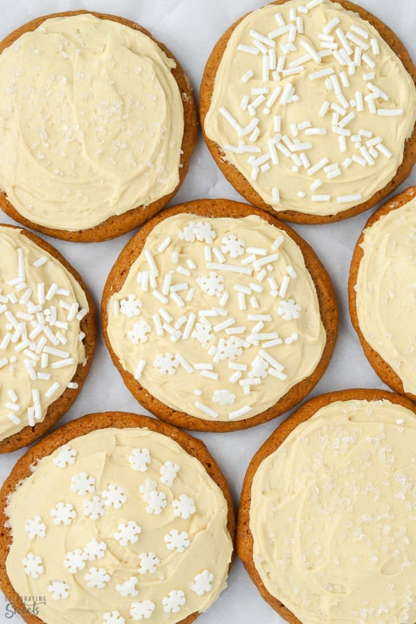 Molasses cookies topped with frosting and white sprinkles.