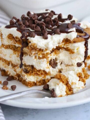 A piece of icebox cake topped with chocolate chips on a white plate.