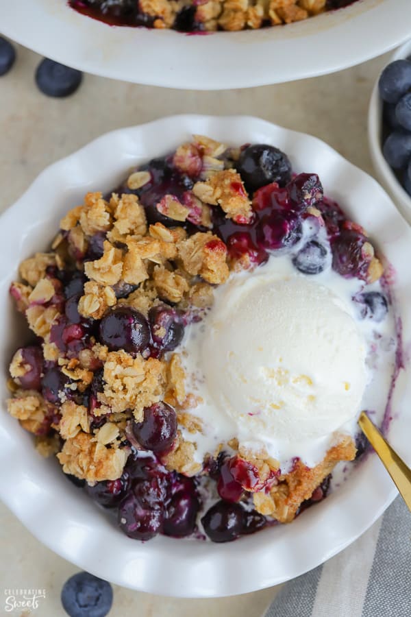Blueberry Crisp topped with ice cream in a white bowl.