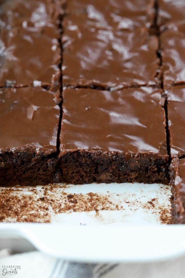 Brownies topped with chocolate icing in a white pan.
