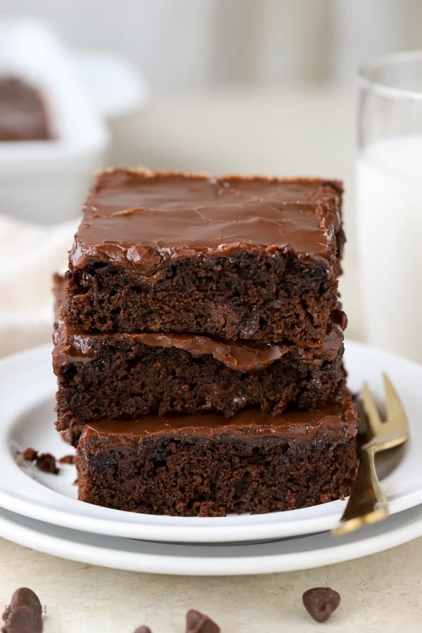 Stack of three brownies on a white plate.