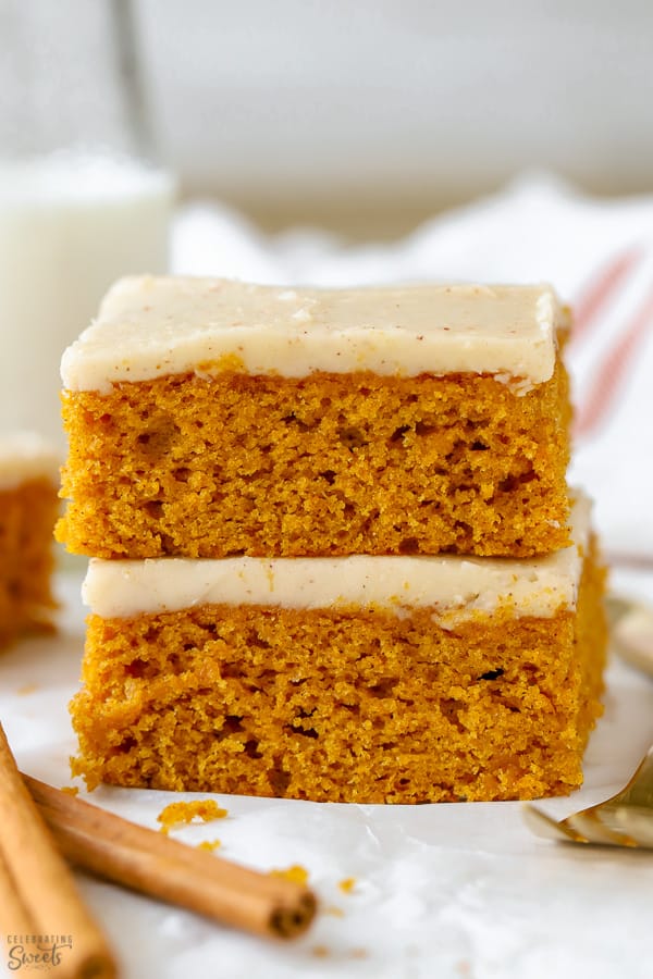 Sliced pumpkin bars topped with frosting on a piece of parchment paper.