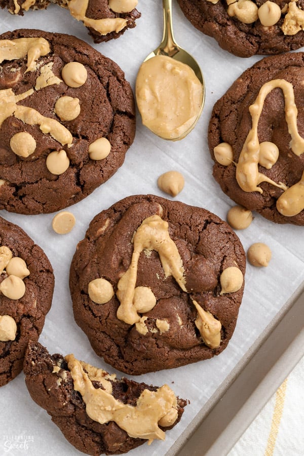 Baking sheet with chocolate cookies, peanut butter chips, and a spoonful of peanut butter