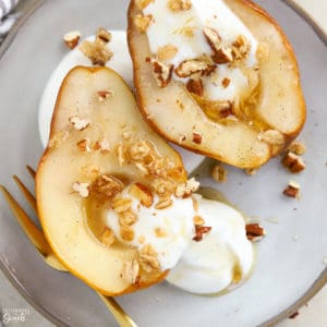 Baked pears on a plate with yogurt and granola.