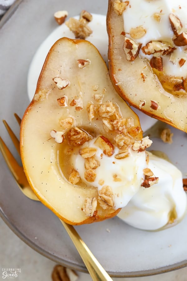 Baked pears on a plate with yogurt and granola.