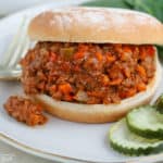 Sloppy joe sandwich on a plate with pickles
