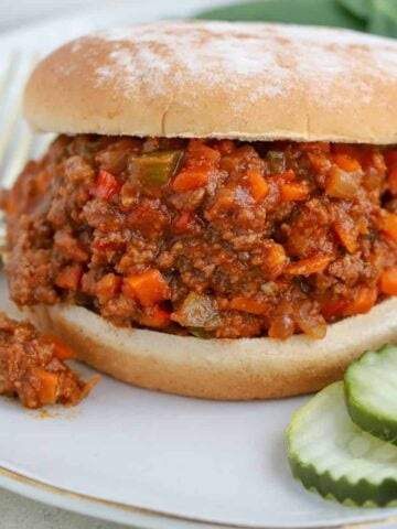 Sloppy joe sandwich on a plate with pickles