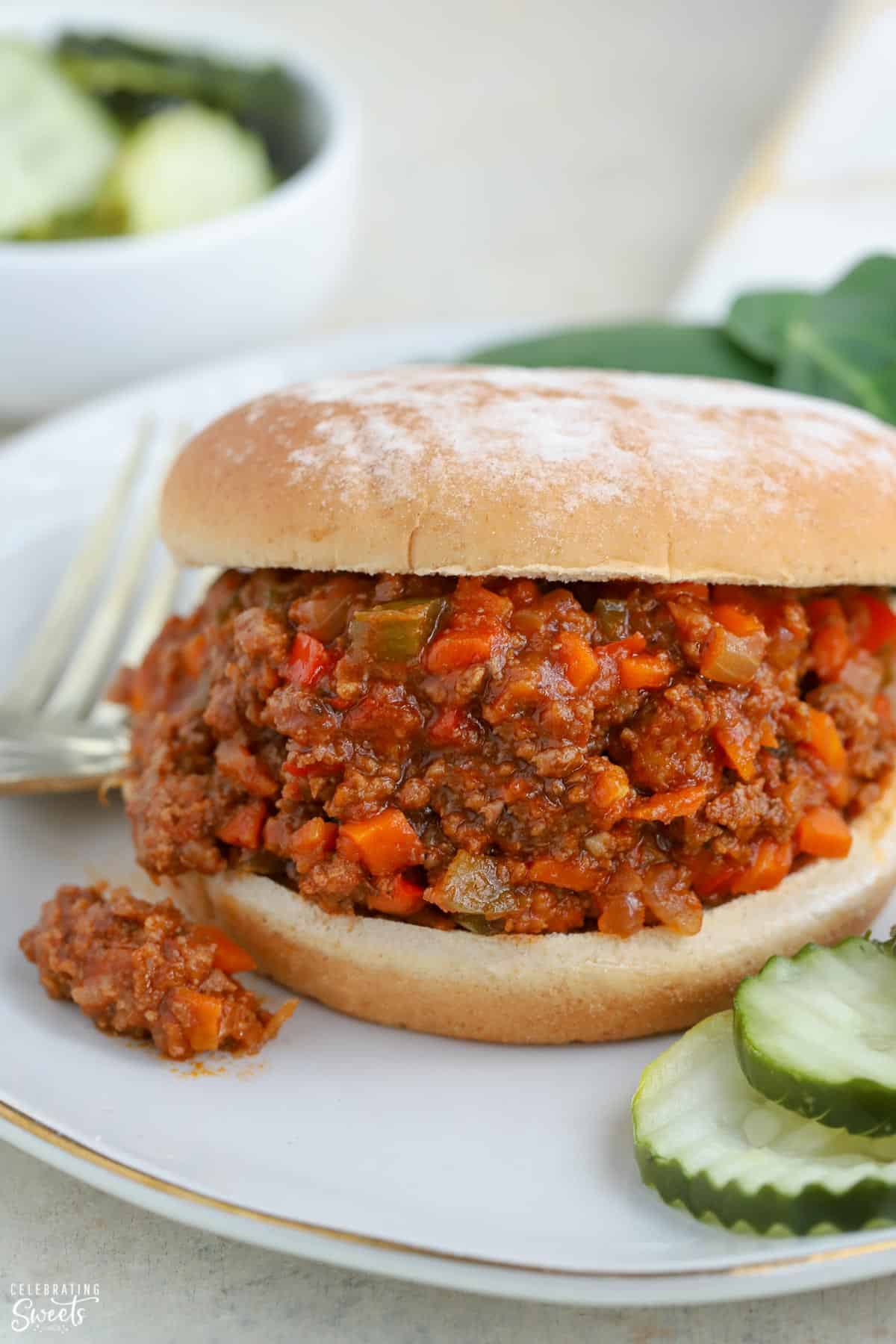 Sloppy joe sandwich on a plate with pickles