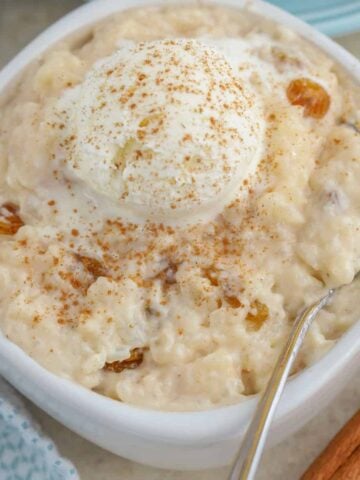 Rice pudding in a white bowl topped with ice cream and cinnamon.