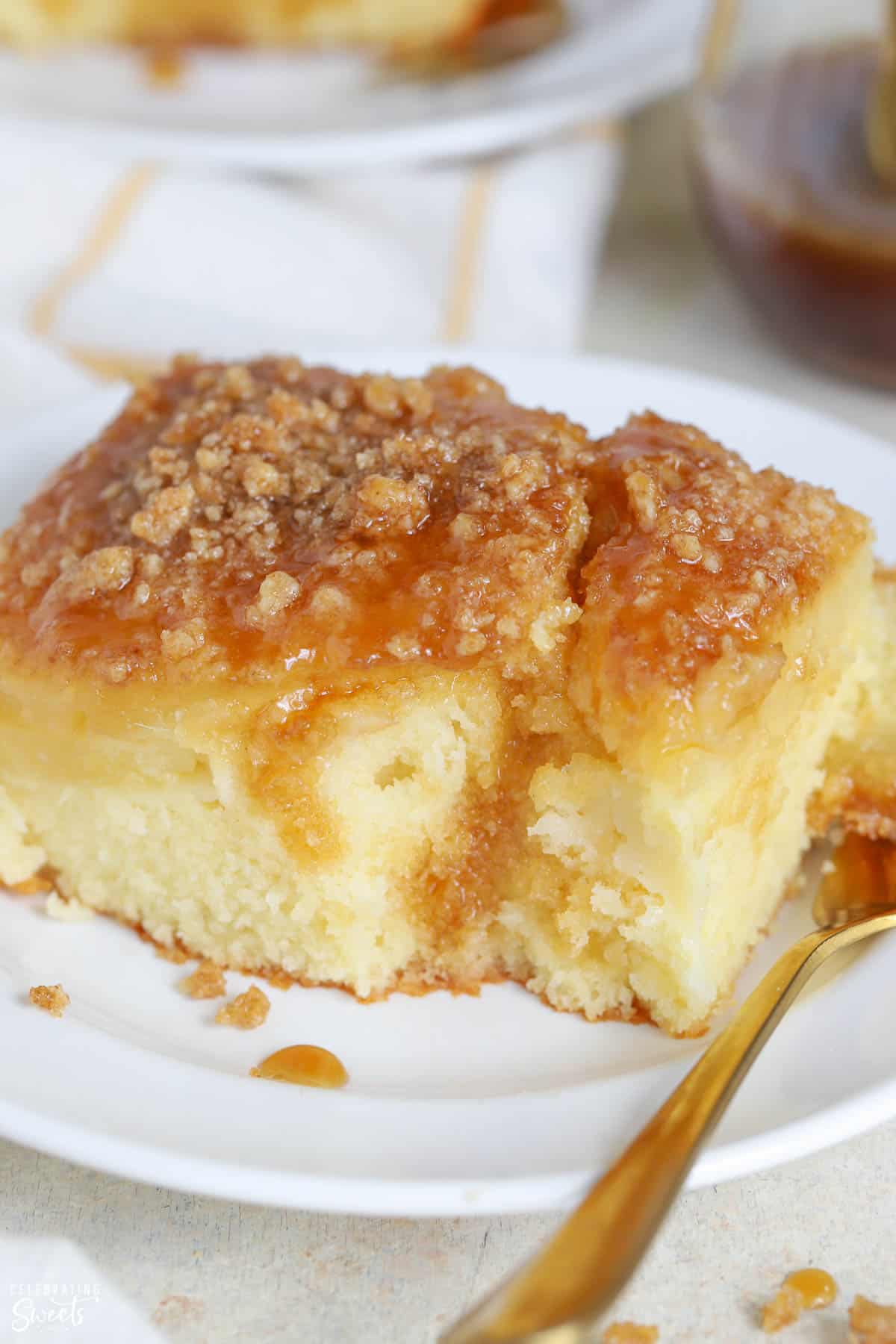 Slice of pineapple cake topped with crumble and brown sugar sauce on a white plate