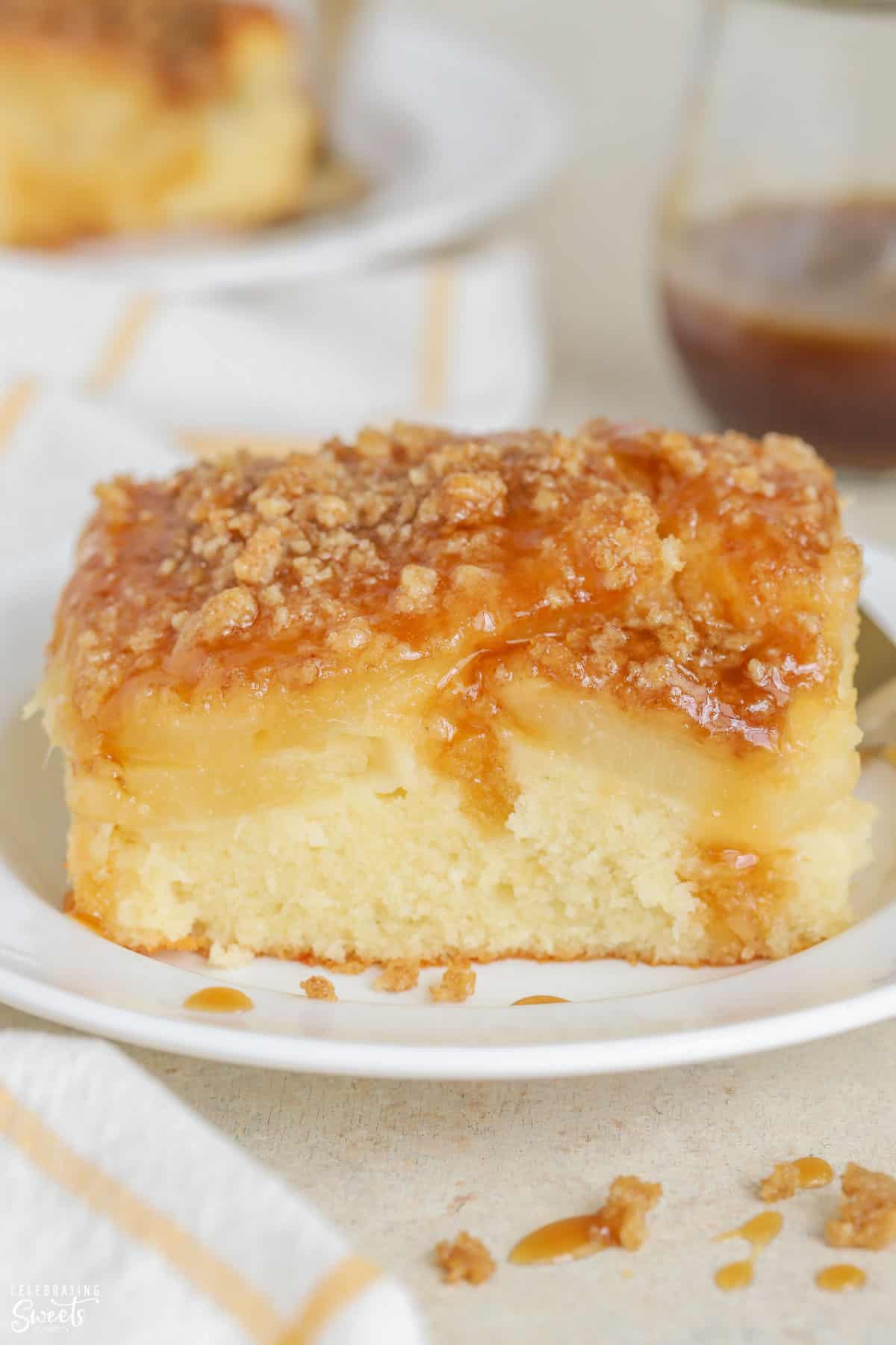 Slice of pineapple cake topped with crumble and brown sugar sauce on a white plate