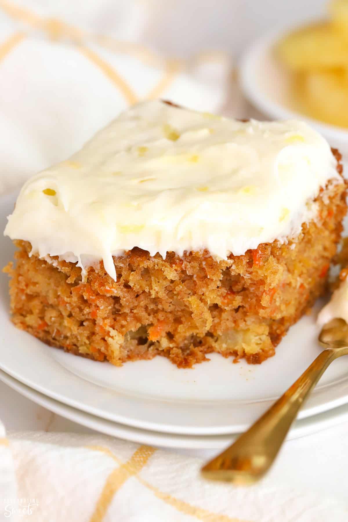 Slice of Pineapple Carrot Cake on a white plate with a gold fork