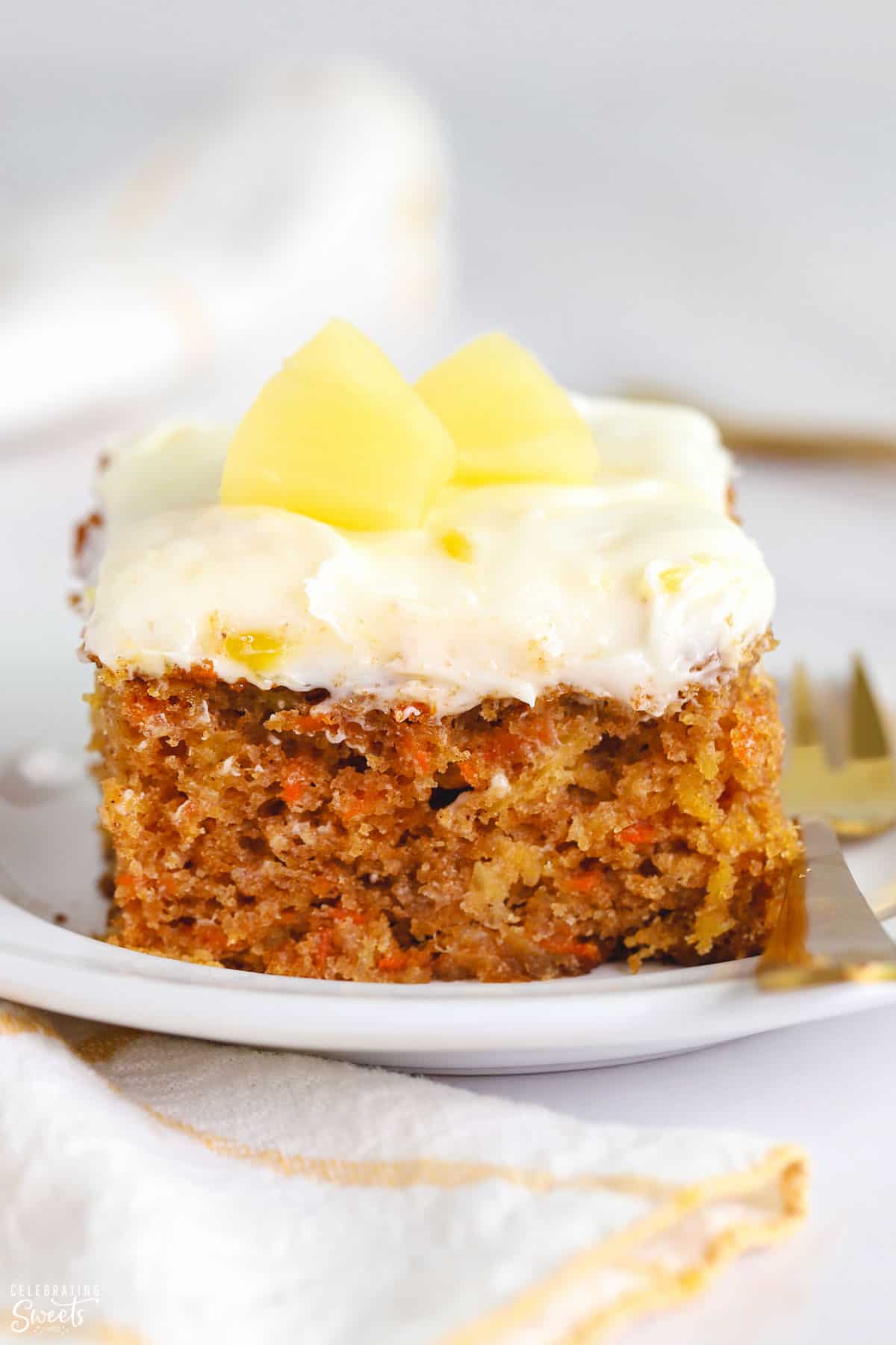 Slice of pineapple carrot cake on a white plate topped with pineapple
