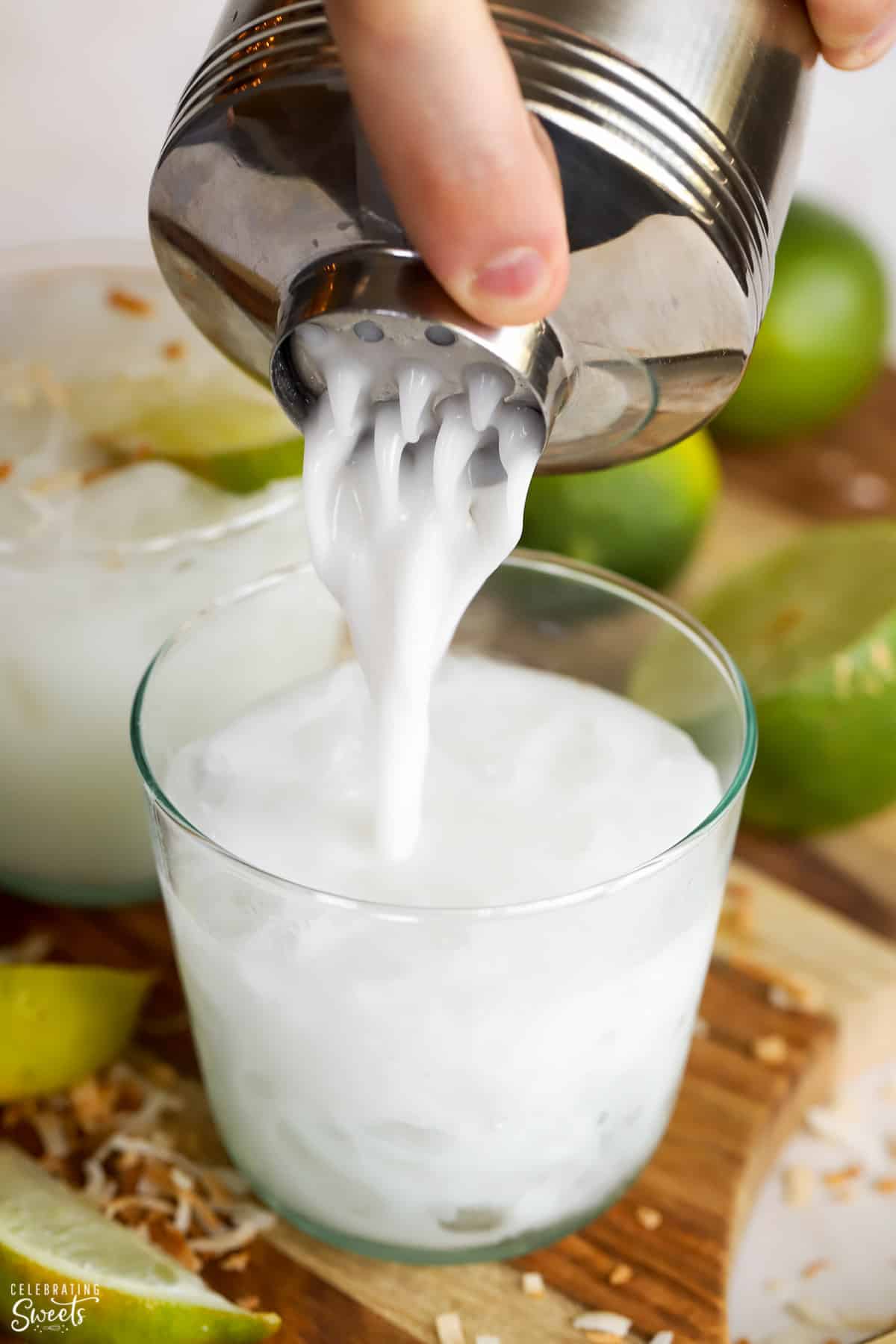 Coconut margarita being poured from a cocktail shaker into a glass