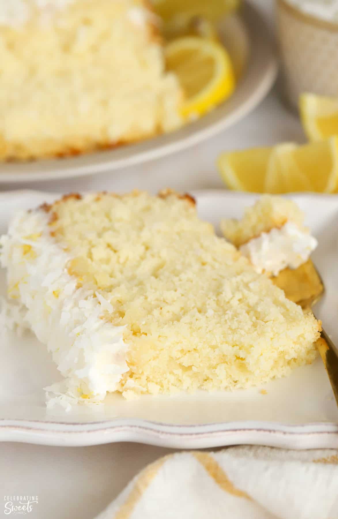 Slice of lemon coconut cake on a white plate with a gold fork