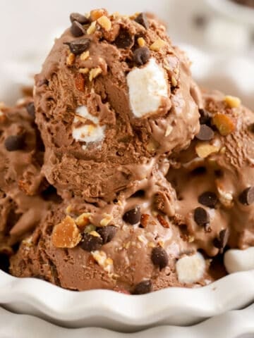 Closeup of a white bowl filled with scoops of rocky road ice cream.