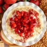 Cheesecake dip in a white bowl topped with strawberries