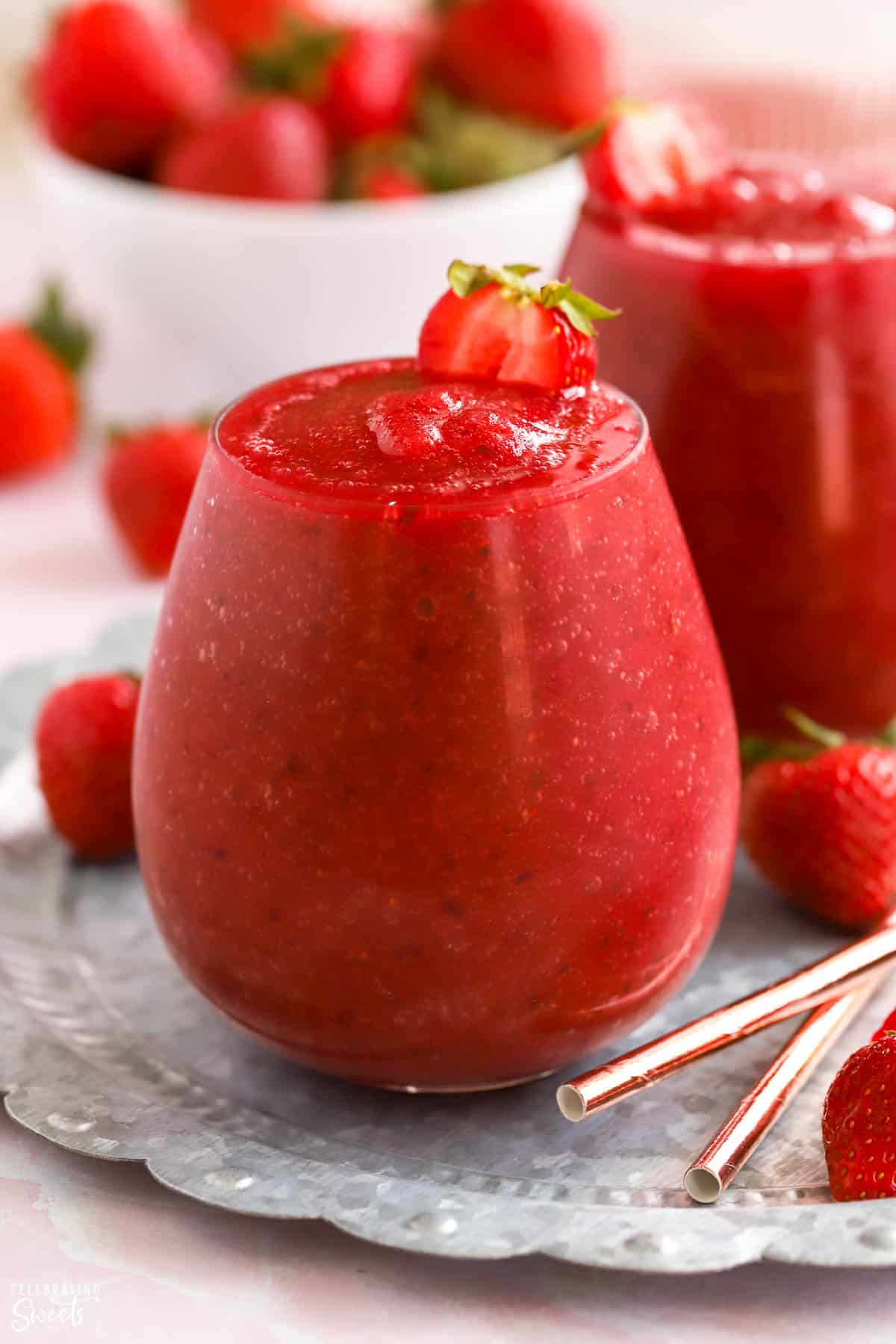 Dark red Frosé wine slushies in a glass garnished with strawberries.