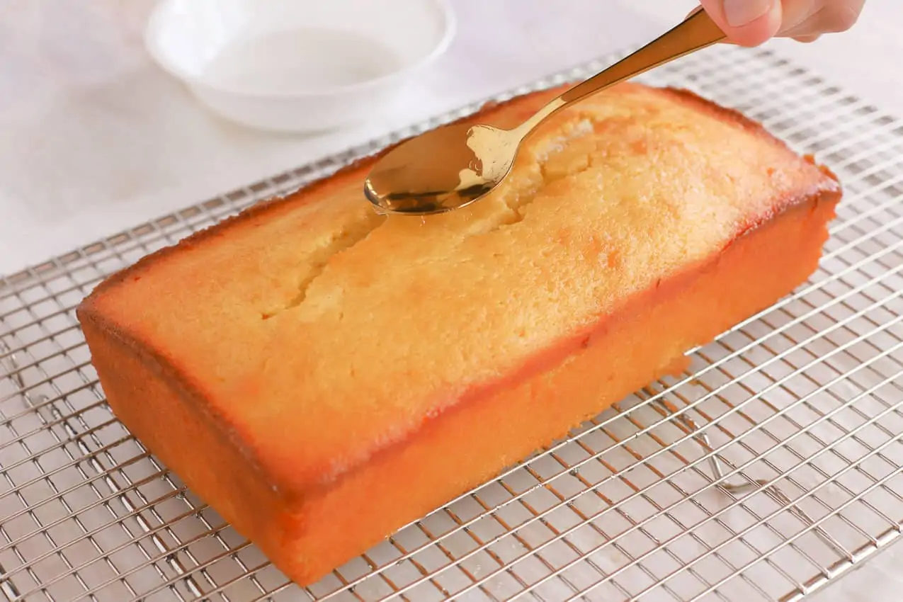 Syrup being drizzled on a loaf cake