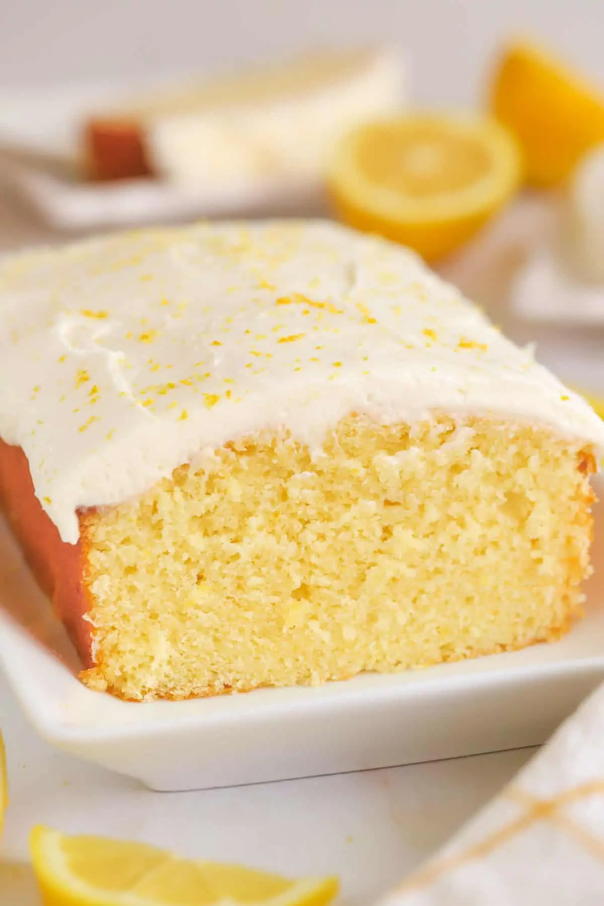 Lemon loaf cake topped with frosting on a white plate.