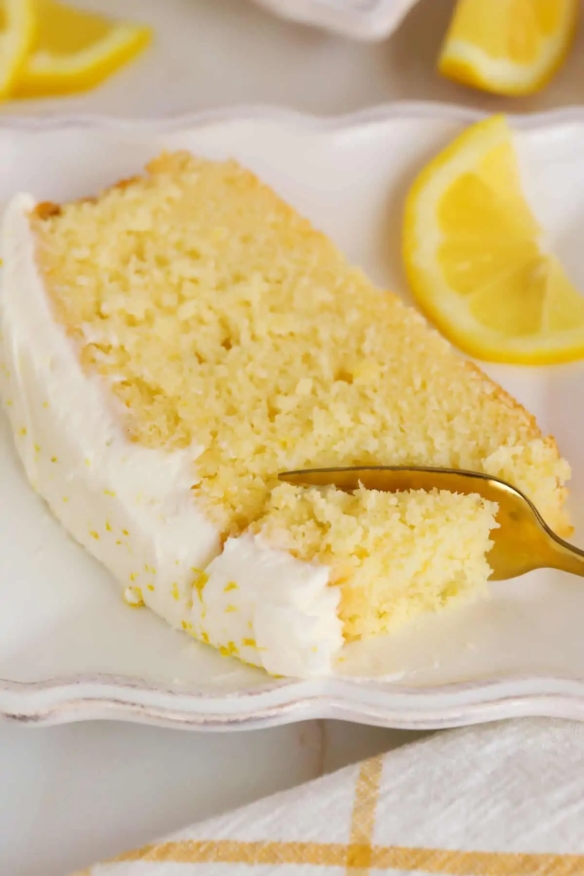 Slice of lemon loaf cake on a white plate with a gold fork.