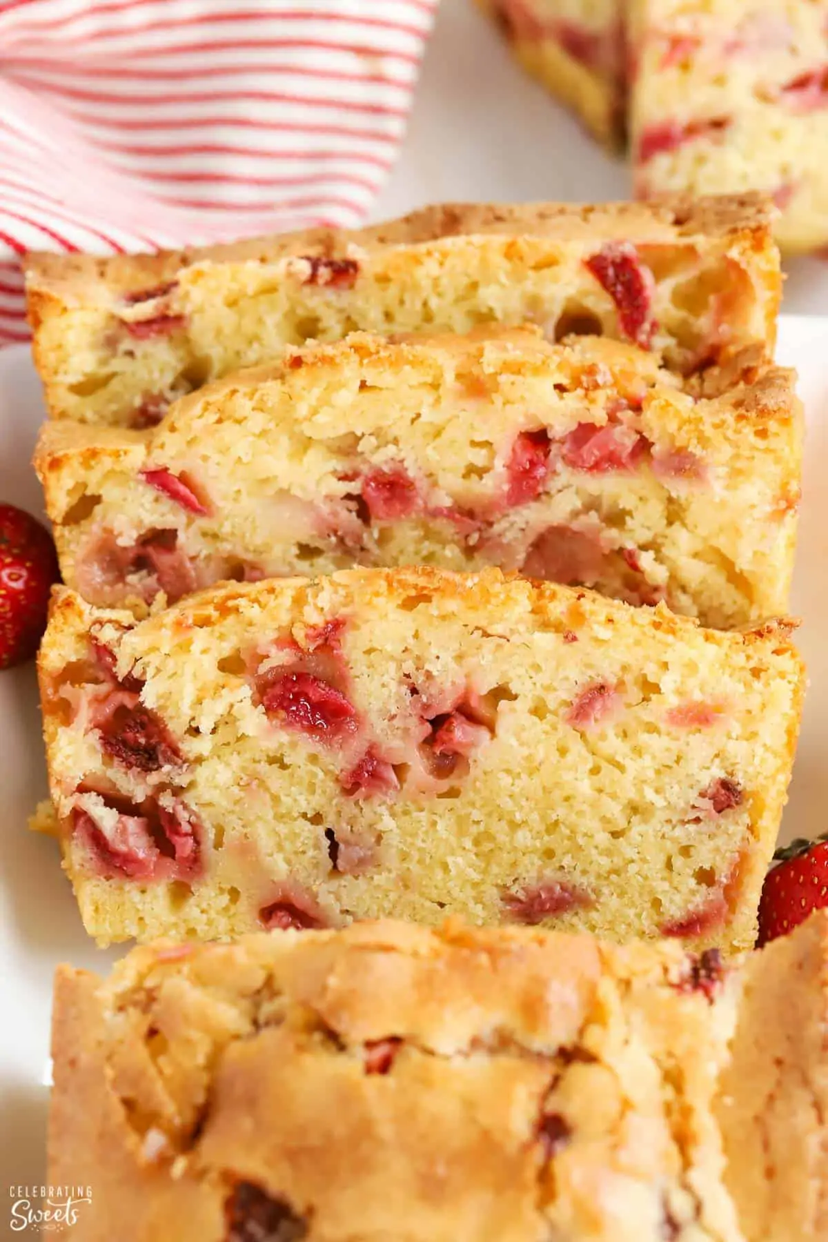 Slices of strawberry bread on a white plate with a red and white striped napkin in the background.
