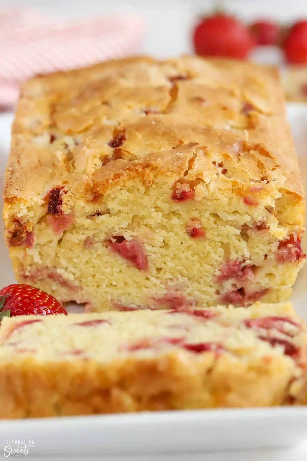 Loaf of strawberry bread on a white plate garnished with strawberries.