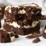 Stack of two cream cheese brownies on a piece of parchment.