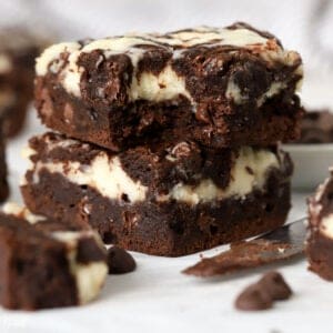 Stack of two cream cheese brownies on a piece of parchment.