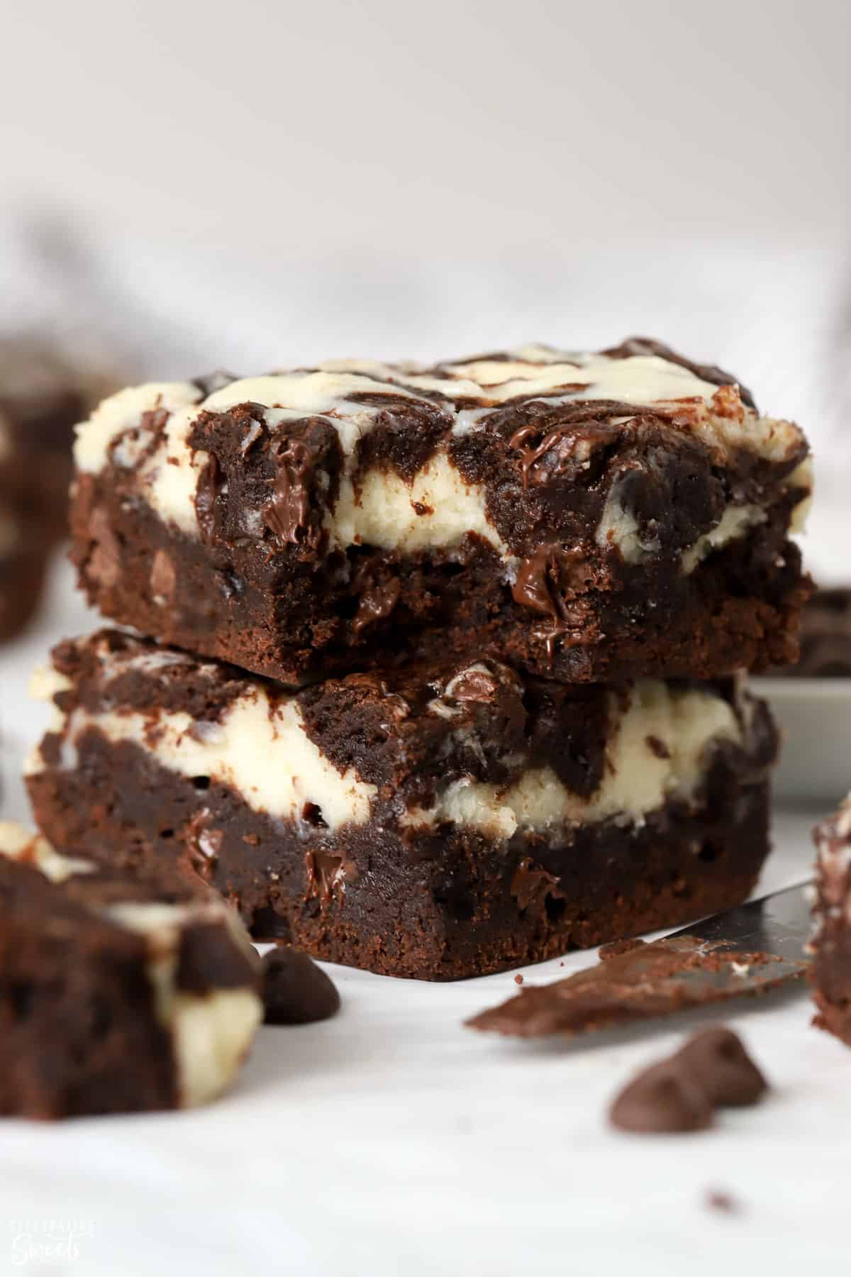 Stack of two cream cheese brownies on parchment paper.