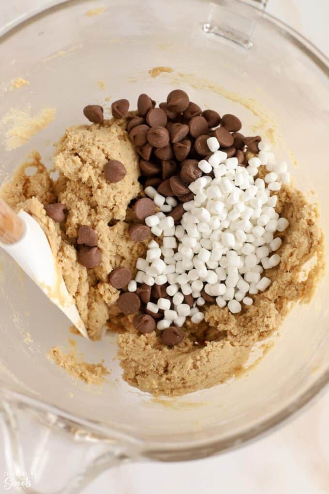 Cookie dough, chocolate chips, and mini marshmallows in a glass bowl.