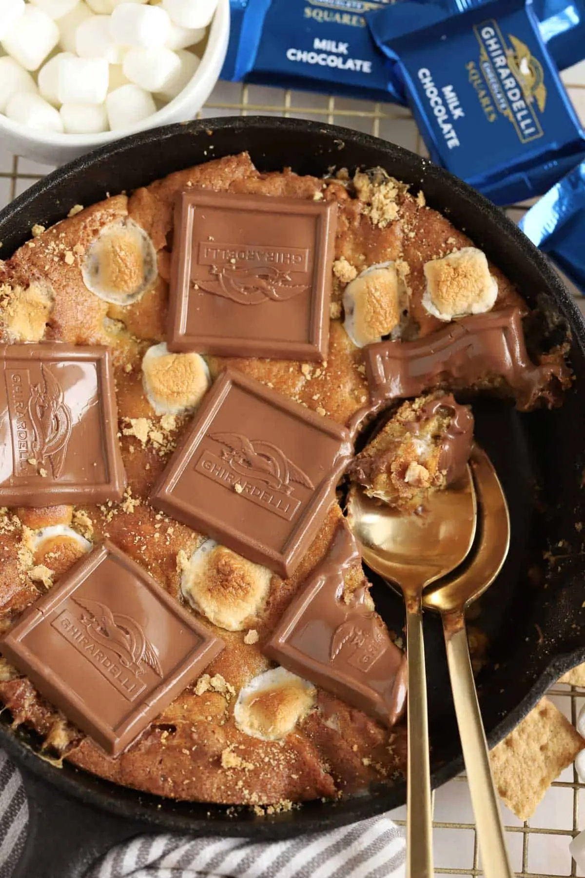 Smores skillet cookie topped with squares of chocolate and toasted marshmallows in a cast iron skillet.