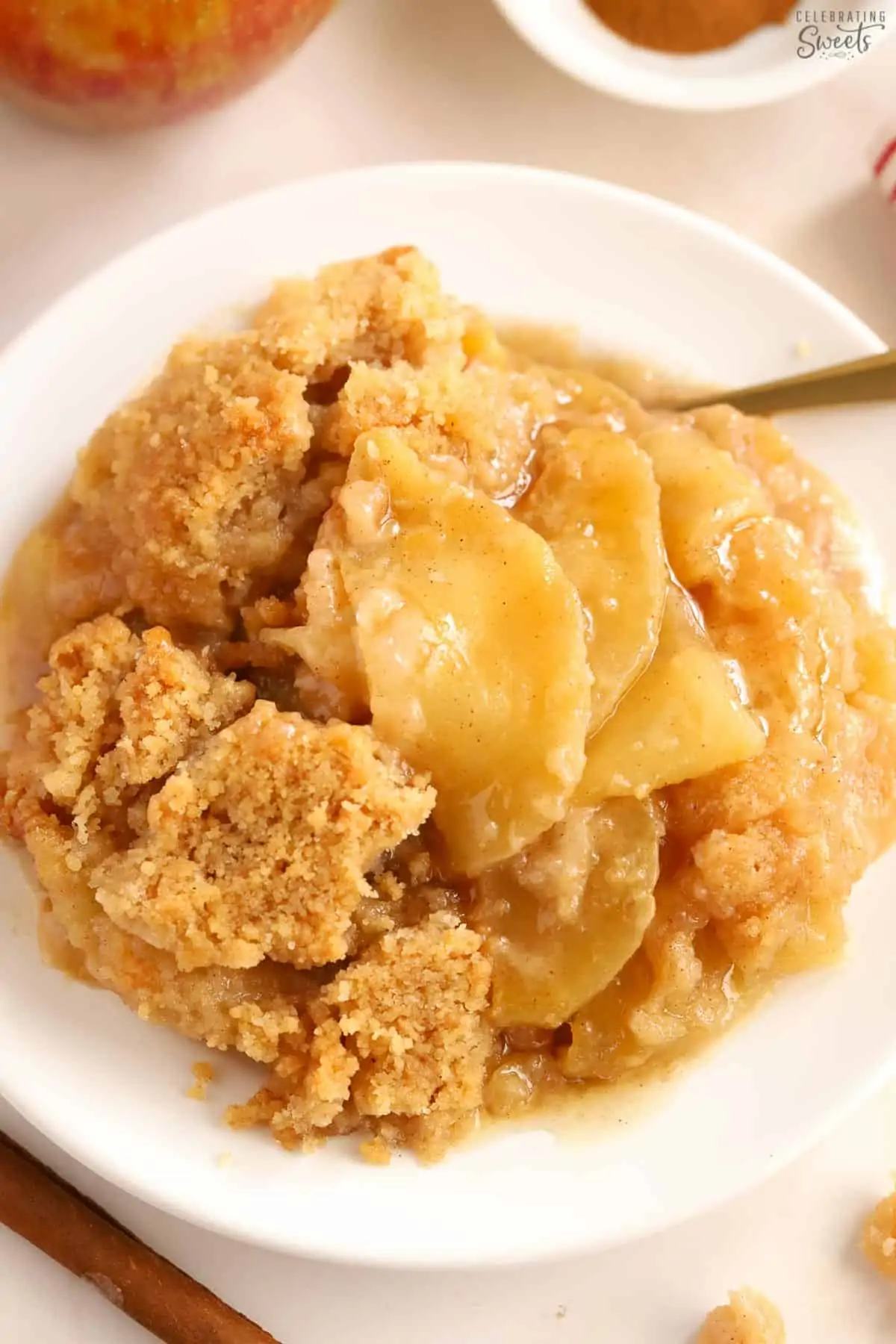 Apple crumble on a white plate with a gold fork.