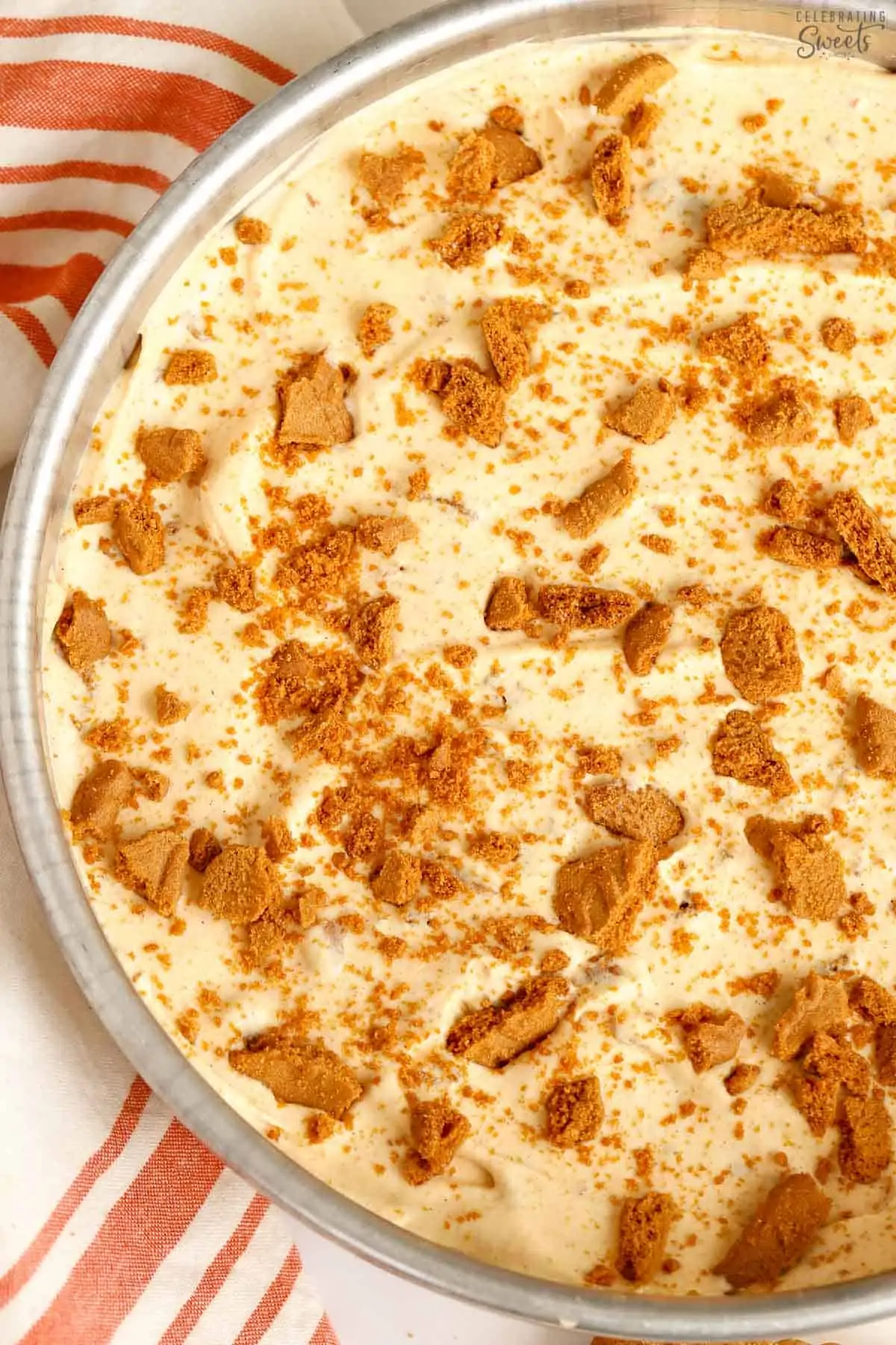 Pumpkin ice cream in a metal pan topped with crushed cookies.