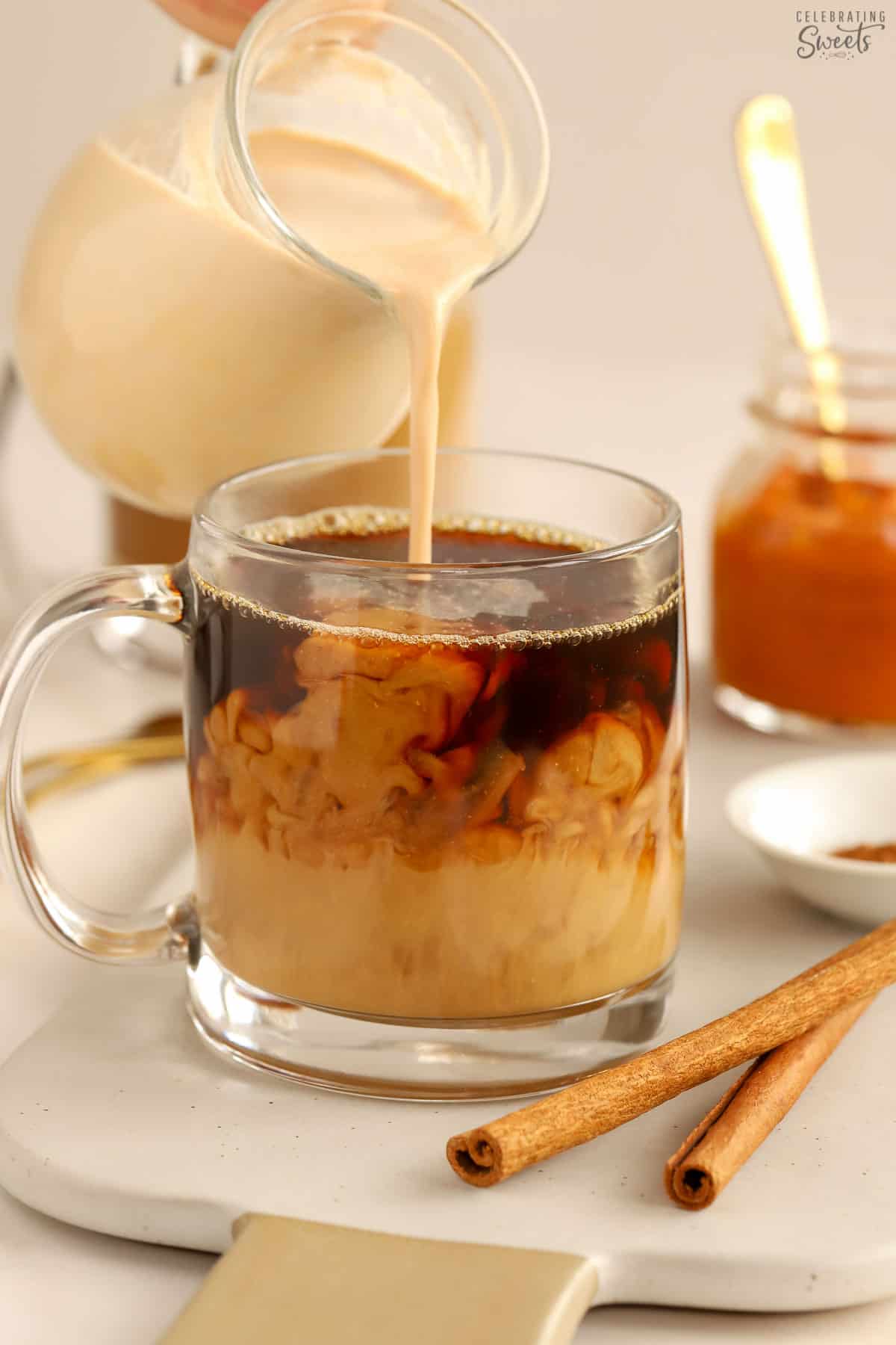 Pumpkin spice creamer being poured into a mug of black coffee.
